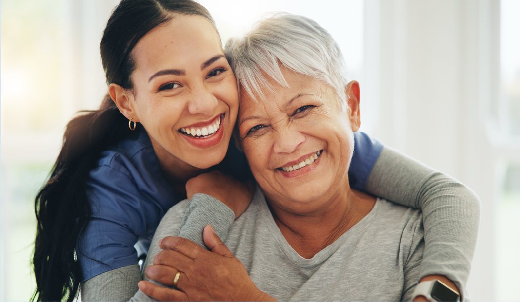 A nurse and a patient smiling together in an embrace