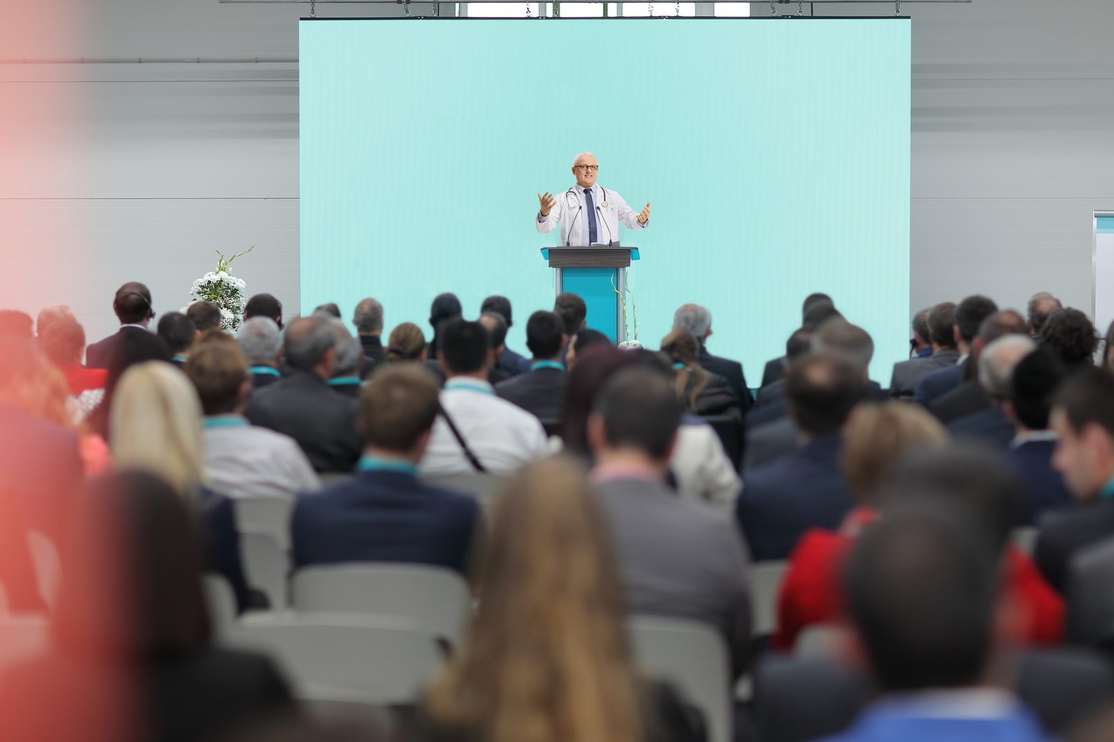 Audience seated at a healthcare symposium watching a keynote presentation